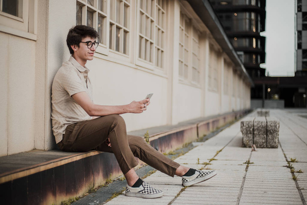 ritratto all'aperto di giovane uomo in occhiali utilizzando il telefono cellulare
  - Foto, immagini