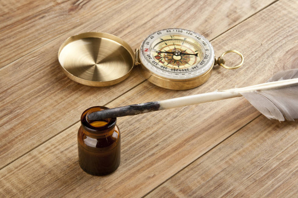 kompas i pióro z tuszu na drewnianym stole - Zdjęcie, obraz