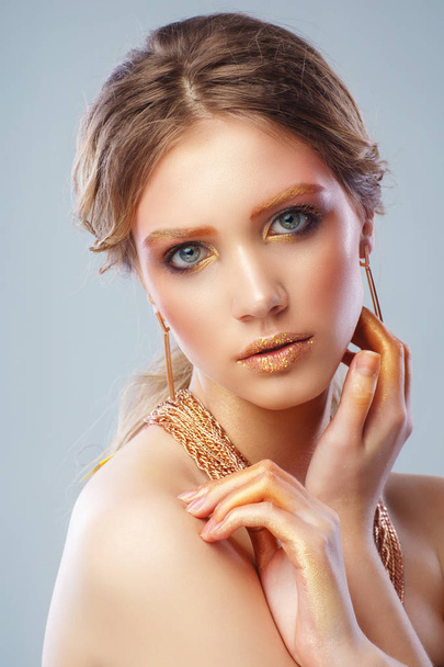 Portrait of stylish blonde woman with holiday bronze makeup and layered chain necklace looking at camera - Valokuva, kuva