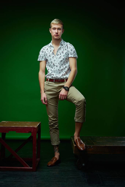 Handsome young man in stylish clothes posing against green studio background  - Fotó, kép