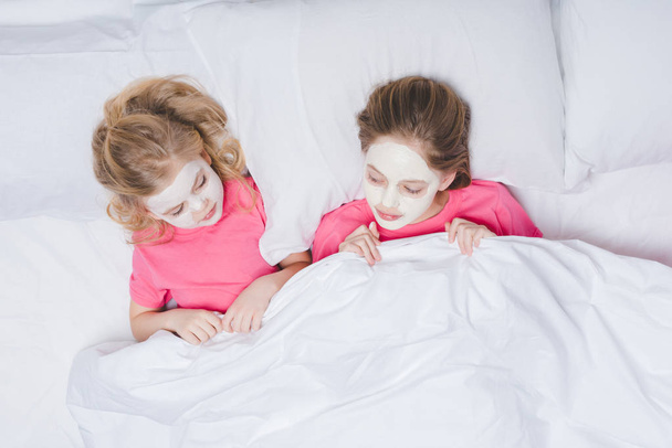 Draufsicht von Schwestern mit Gesichtsmasken, die im Bett liegen - Foto, Bild