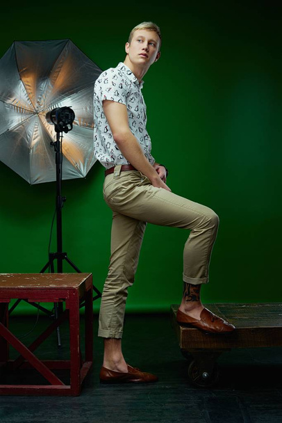 Handsome young man in stylish clothes posing against green studio background  - Foto, afbeelding