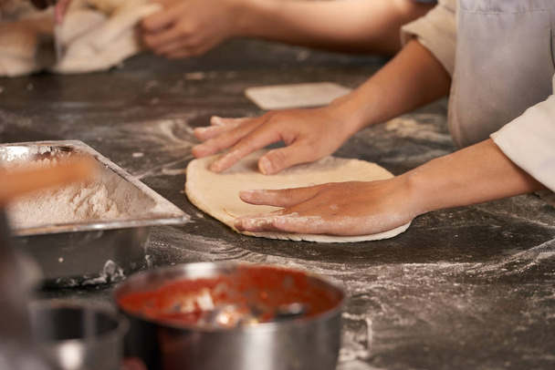 Hands of cook preparing dough for pizza - Foto, Imagen