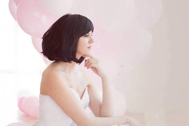 Young woman in wedding dress in luxury interior with a mass of pink and white balloons. - Photo, Image
