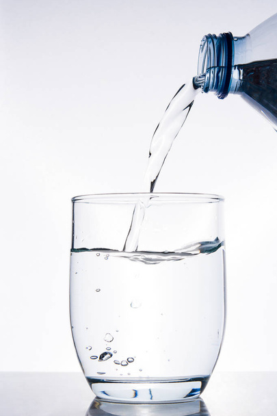 Пляшка води наливає воду в склянку
 - Фото, зображення