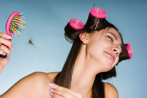 a woman in hair curlers is upset because of hair loss - Foto, Imagem