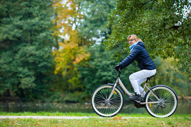 Healthy lifestyle - woman riding bicycle in city park - Foto, imagen