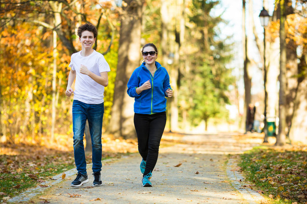 Teenage girl and boy running in city park - Zdjęcie, obraz