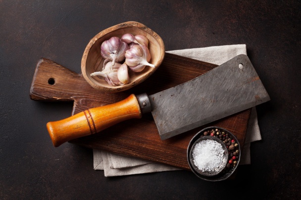 Мясник. Винтажный мясной нож и специи над каменной доской. Вид сверху
 - Фото, изображение