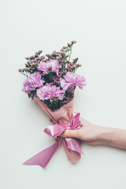 cropped shot of person holding beautiful elegant bouquet of tender purple flowers with ribbon isolated on grey - Фото, изображение