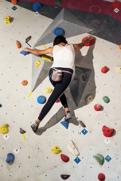 Donna che pratica arrampicata su parete artificiale al chiuso. Stile di vita attivo e concetto di bouldering. - Foto, immagini