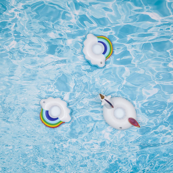 Flotadores de piscina para niños, anillos flotando en una refrescante piscina azul
 - Foto, Imagen