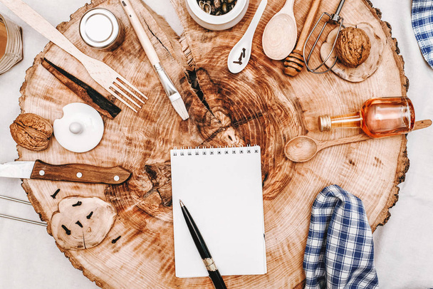 Composition décorative en bois scié avec cahier, stylo et différents ustensiles de cuisine
 - Photo, image