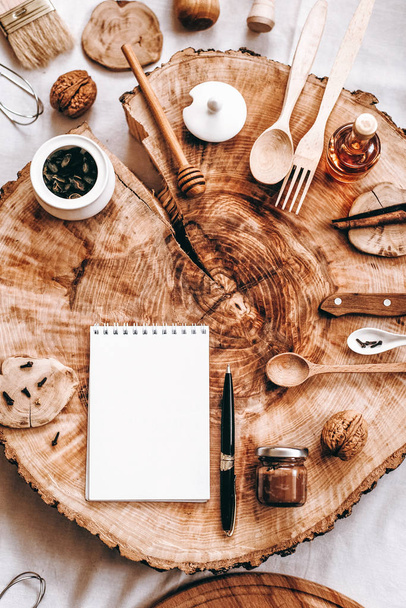 Κάτοψη του κομμένο ξύλο με το σημειωματάριο, στυλό και αξεσουάρ κουζίνας σε φόντο - Φωτογραφία, εικόνα