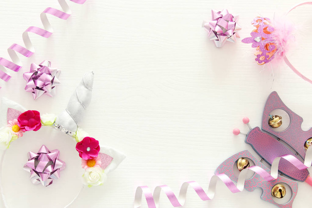 girl's party concept. unicorn head decoration, pink wand and toy over white wooden background. - Photo, Image