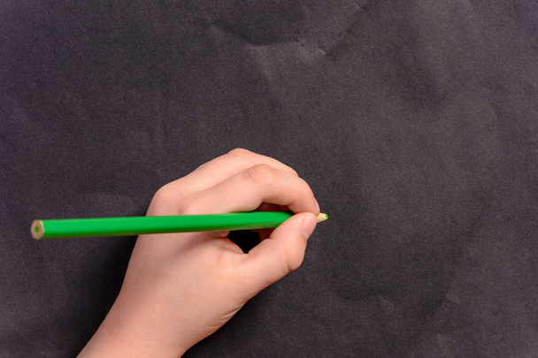 La mano di un bambino scrive una matita su uno sfondo nero
 - Foto, immagini