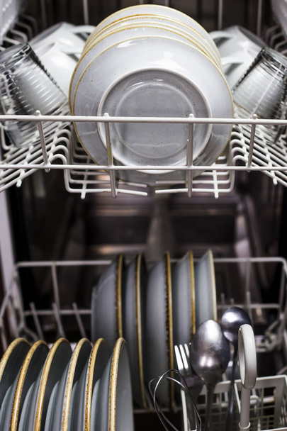 Czystymi naczyniami i inne sztućce w zmywarce. Sprzęt do domu. Niebieski rustykalne naczynia - Zdjęcie, obraz