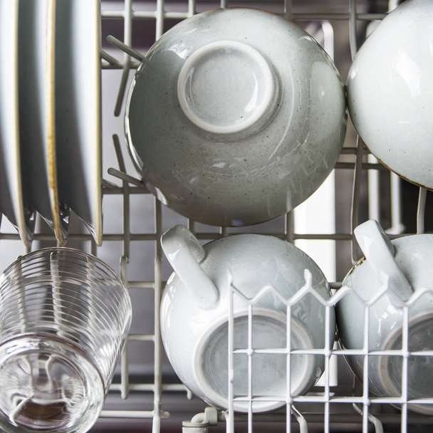Limpia los platos y tazas en el lavavajillas. Equipo doméstico. Vajilla rústica azul
 - Foto, Imagen