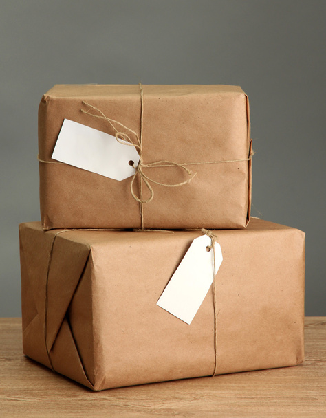 parcels boxes with kraft paper, on wooden table on grey background - Фото, зображення