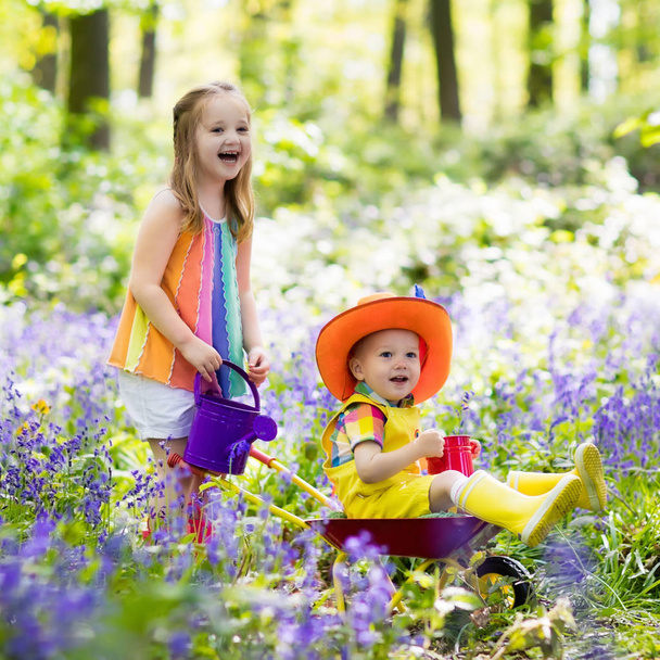 Kids with bluebell flowers, garden tools - Photo, Image