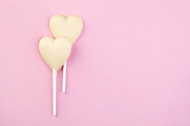 Two white chocolate candy hearts on pink  - Foto, Bild