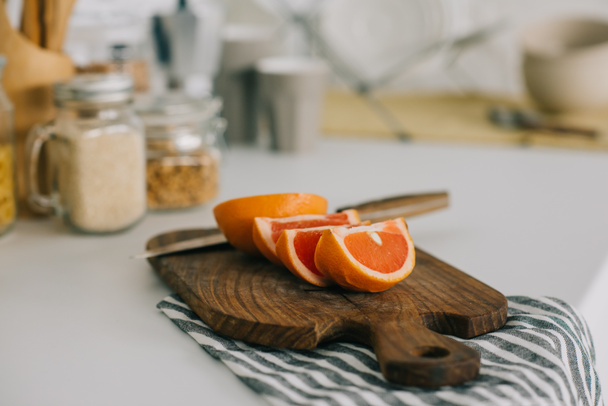 cut grapefruit with knife on cutting board in kitchen - 写真・画像