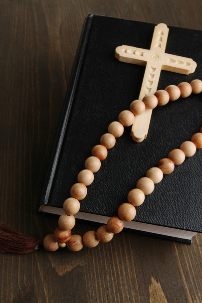 Bible, rosary and cross on wooden table close-up - Foto, afbeelding