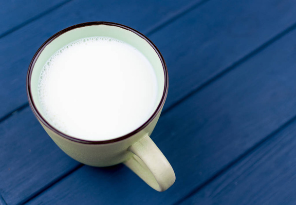 A large cup of milk on a blue background. - Fotoğraf, Görsel