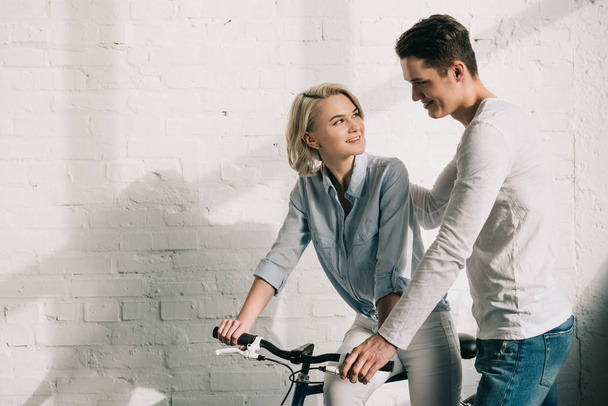 boyfriend hugging girlfriend sitting on bicycle at home - Photo, image