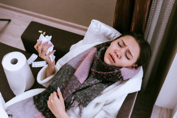 a sick woman with a warm scarf lies on the bed - Zdjęcie, obraz