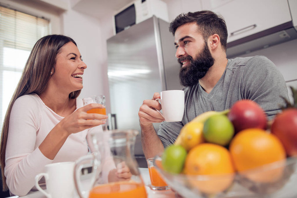 Fiatal boldog pár ül a modern lakásban, és együtt reggeliznek. - Fotó, kép