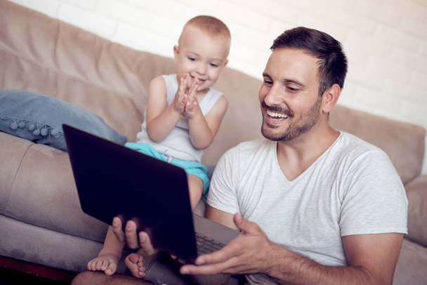 家族、父権、技術と人の概念幸せな父と幼い息子と自宅のソファに座ってノート パソコン. - 写真・画像