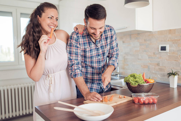 Romantik genç çift birlikte mutfakta yemek. Kesme sebze birlikteler. - Fotoğraf, Görsel