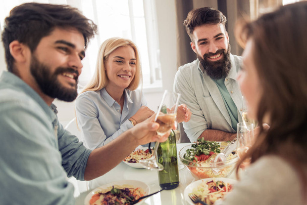 Grupo de jóvenes amigos felices comiendo y divirtiéndose en casa.Ocio, comida, diversión y concepto de personas. - Foto, imagen