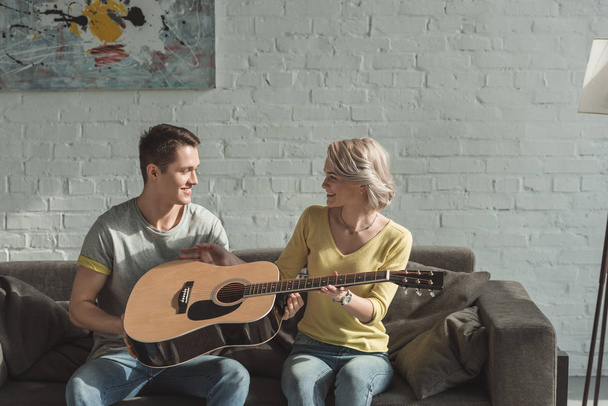 boyfriend giving acoustic guitar to girlfriend at home - Foto, Imagen