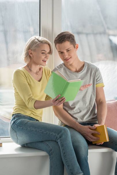 happy girlfriend showing book to boyfriend at home - Photo, image