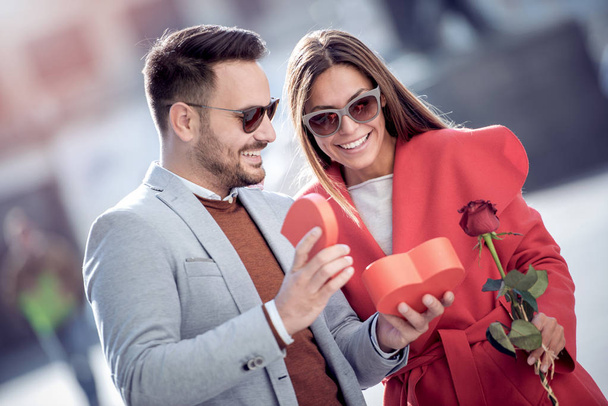 Valentine's day obecny. Człowiek, prezentując prezent i kwiaty jego dziewczyna, widuje się na ulicy. Obchodzi, relacje, rodzic, miłości i romantyczna koncepcja. - Zdjęcie, obraz