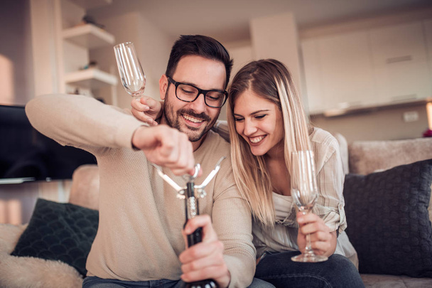 Beautiful young couple with glasses of red wine in living room. - Foto, imagen