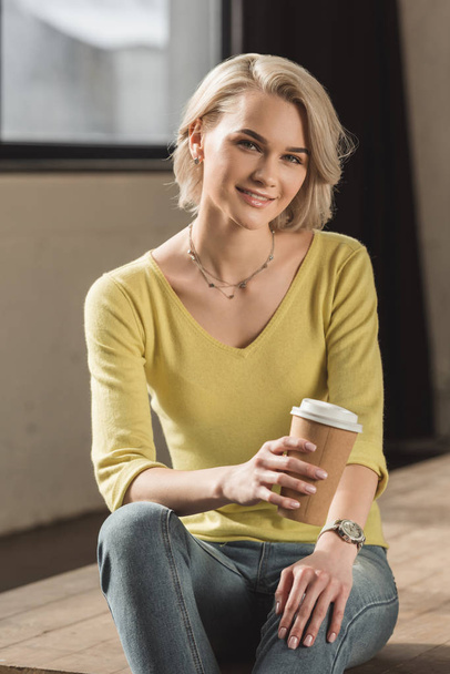 χαμογελαστό κορίτσι κρατώντας φλιτζάνι καφέ μίας χρήσης και να βλέπουν τα φωτογραφικών μηχανών - Φωτογραφία, εικόνα