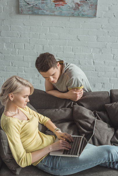girlfriend using laptop and boyfriend looking at screen at home - Φωτογραφία, εικόνα