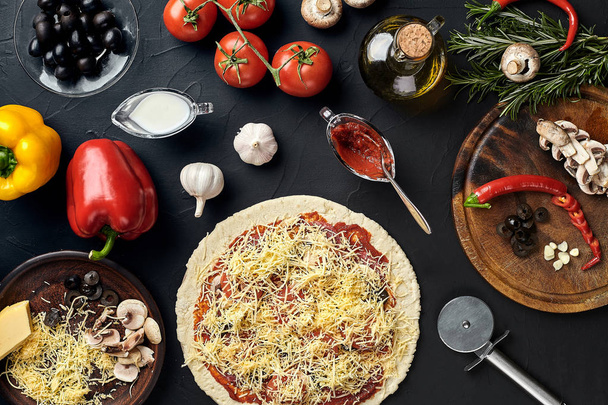 Сырая пицца ингредиенты на фоне черной текстуры стола
 - Фото, изображение