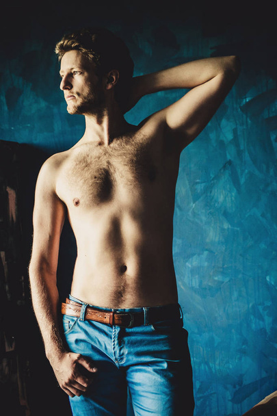 Porträt eines jungen, hemdslosen, gutaussehenden Mannes auf dunkelblauem Hintergrund  - Foto, Bild