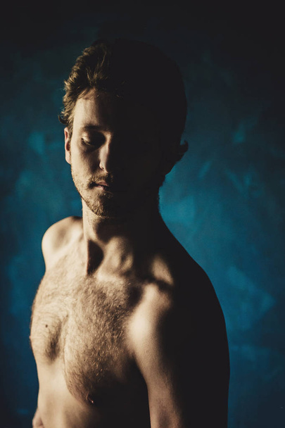 portrait of young shirtless handsome man on dark blue background  - 写真・画像
