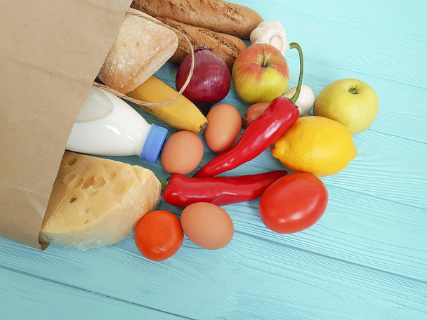 χαρτί τσάντα με διάφορα χρήσιμα τρόφιμα, λαχανικά και φρούτα σε μπλε ξύλινο - Φωτογραφία, εικόνα