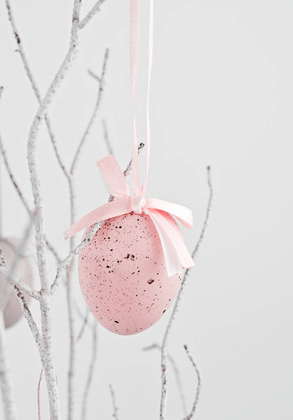 Vaaleanpunainen koriste muna roikkuu kuivalla oksalla
 - Valokuva, kuva