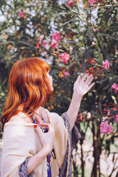 beautiful woman with red hair looks at flowers - Foto, immagini