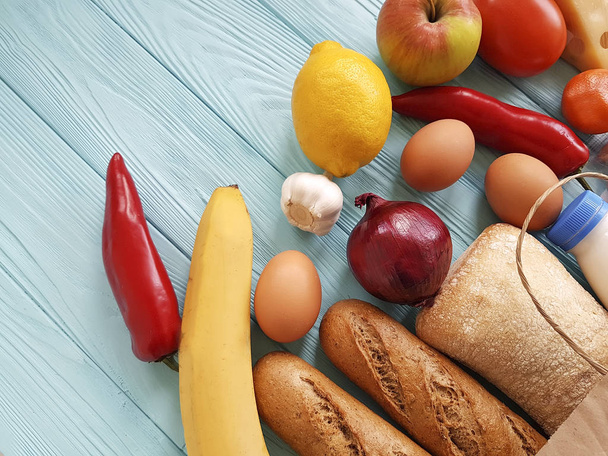 χαρτί τσάντα με διάφορα χρήσιμα τρόφιμα, λαχανικά και φρούτα σε μπλε ξύλινο - Φωτογραφία, εικόνα