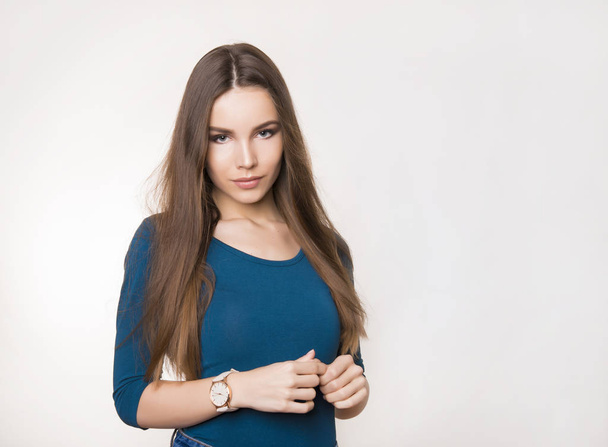 beautiful young woman with long brown hair wearing wrist watch and posing in grey background with copy space - Foto, Imagem