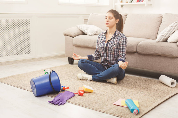 Mujer meditando mientras limpia su casa
 - Foto, Imagen