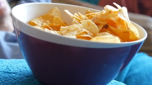 Large plate with potato chips. The woman lies on the couch and eating potato chips, close up view - Materiał filmowy, wideo